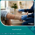 طبيب متخصص يقوم بتطبيق ضمادة ضاغطة على ساق مريض لعلاج القرحة الوريدية في عيادة حديثة.