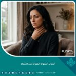 امرأة تشعر بالقلق وتضع يدها على رقبتها بسبب خشونة الصوت، مما يعكس مسببات وبحة الصوت عند النساء.