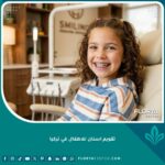 طفل سعيد يبتسم بثقة مع تقويم أسنان ملون، يمثل جودة العناية في تقويم أسنان الأطفال في تركيا.