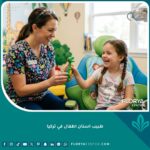 طبيب أسنان أطفال في تركيا يتعامل بلطف مع طفل مبتسم داخل عيادة أسنان حديثة ومريحة.