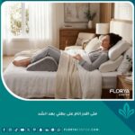 امرأة تنام براحة على ظهرها باستخدام الوسائد الداعمة بعد عملية شد البطن لتجنب ألم الظهر.